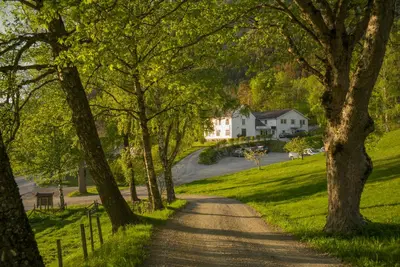a dirt road with a house in the distance at Hotel Aak in Åndalsnes