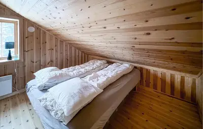 a bed in a room with a wooden wall at 2 Bedroom Nice Home In Aust- Torpa in Aust-Torpa
