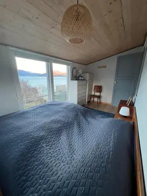 a bedroom with a large bed with a large window at Turer, avslapping, jakt, fiske, utsikt in Etnesjøen
