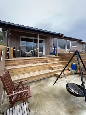 a house with a wooden deck with a chair at Turer, avslapping, jakt, fiske, utsikt in Etnesjøen