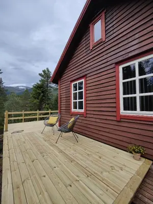 a wooden deck with two chairs on top of a house at Tronstadbu- 1800s Cabin near Geirangerfjord & Slogen Hike in Hellesylt