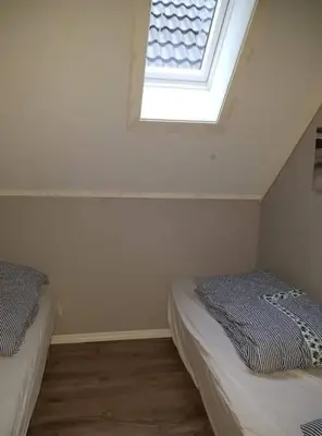 a attic room with two beds and a window at Rorbu i Austevoll med 3 soverom og mulighet for båtleie in Kolbeinsvik