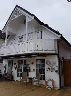 a house with a porch with chairs on a deck at Rorbu i Austevoll med 3 soverom og mulighet for båtleie in Kolbeinsvik