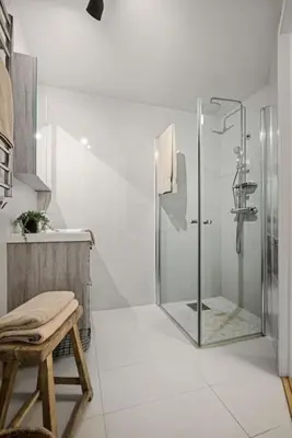 a bathroom with a shower and a stool in it at Modern apartment in the heart of Bergen in Bergen