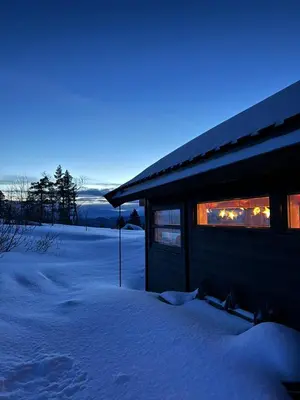 a building in the snow with lights in the windows at Sveheim - cabin with an amazing view in Flå