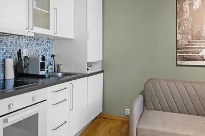 a kitchen with white cabinets and a sink and a chair at Peaceful Urban Residence in Bergen