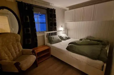 a bedroom with a bed and a chair and a window at Leilighet på Bekkeli, Beito. in Beitostøl