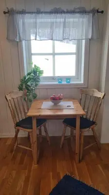 a wooden table with two chairs and a window at Leilighet på Bekkeli, Beito. in Beitostøl