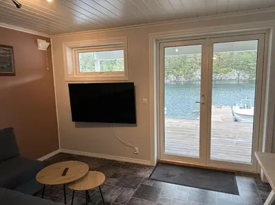 a living room with a flat screen tv on the wall at Rorbu i Gilsvågen - 3 soverom - Båtutleie in Austevoll