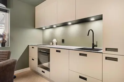 a kitchen with white cabinets and a sink at Bryggen // Fløyen Apartments in Bergen