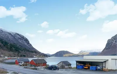 a building next to a body of water with mountains at 2 Bedroom Lovely Home In Innfjorden in Innfjorden