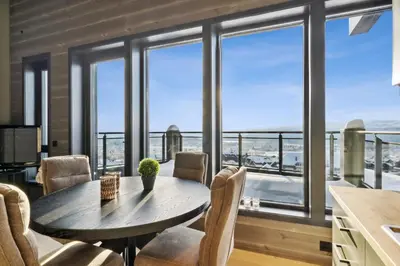 a dining room with a table and chairs and windows at Riddergaardens utsikt in Beitostøl