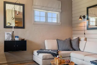 a living room with a couch and a mirror at Beitostølen! Midt i sentrum! Ski in ski out! Badstue-Massasjedusj-Steamdusj in Beitostøl