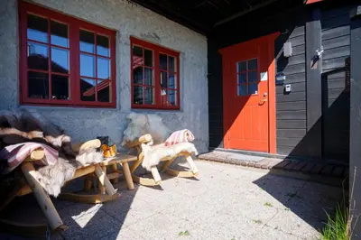 a group of wooden benches outside of a building with a red door at Beitostølen! Midt i sentrum! Ski in ski out! Badstue-Massasjedusj-Steamdusj in Beitostøl
