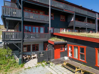 an apartment building with red doors and a patio at Beitostølen! Midt i sentrum! Ski in ski out! Badstue-Massasjedusj-Steamdusj in Beitostøl