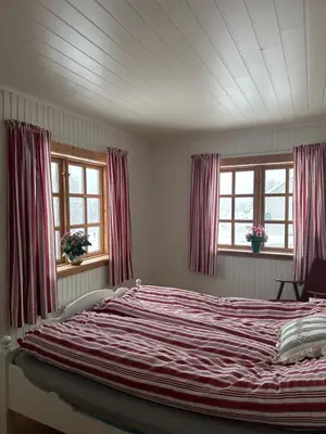 a large bed in a bedroom with two windows at Familievennlig fritidsbolig i hjertet av Flå, perfekt for besøk i Bjørneparken in Flå