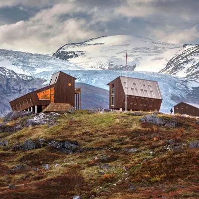 two buildings on a hill with a snow covered mountain at Tungestølen in Veitastrond