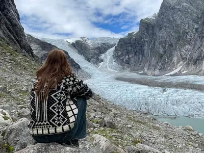 a woman sitting on a mountain looking at a glacier at Tungestølen in Veitastrond