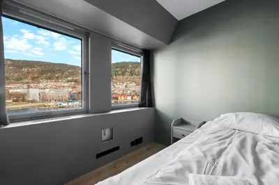 a bedroom with a bed and a large window at Nordnes - Amazing view of Bryggen! in Bergen
