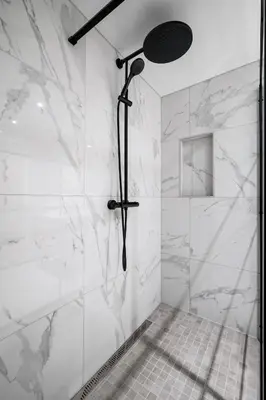 a bathroom with a shower with white marble walls at Nordnes - Amazing view of Bryggen! in Bergen