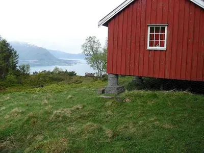 a red house on top of a hill with a window at Orset setra - back to basic cabin - with amazing view in Torvikbukt