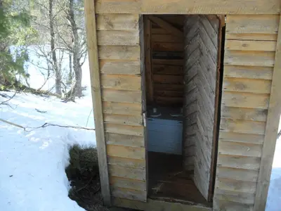 a door in the side of a wooden building in the snow at Orset setra - back to basic cabin - with amazing view in Torvikbukt