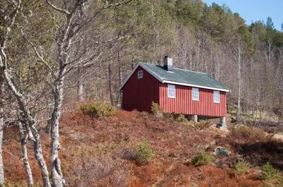 a red barn on a hill in the woods at Orset setra - back to basic cabin - with amazing view in Torvikbukt