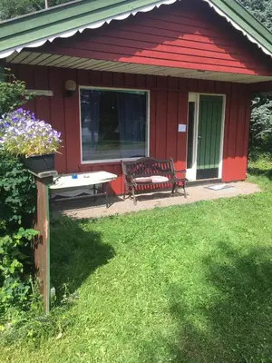 a red shed with a table and chairs in the yard at Rønlund Hyttepark, Midgard in Ron