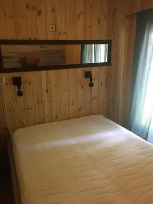 a bed in a room with a wooden wall at Rønlund Hyttepark, Midgard in Ron