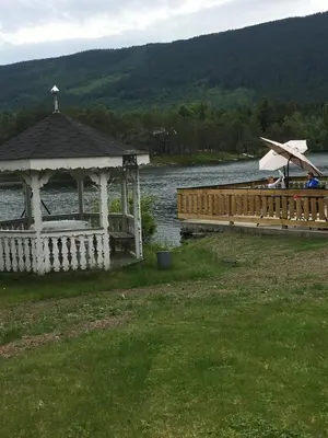 a gazebo next to a river with a bridge at Rønlund Hyttepark, Midgard in Ron