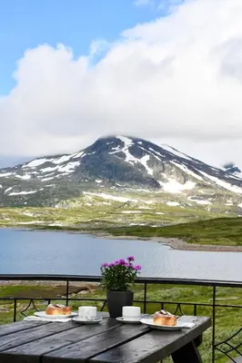 a table with two plates of food and a mountain at Tyinholmen Høyfjellsstuer in Eidsbugarden