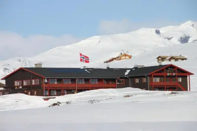 a building with a canadian flag in the snow at Tyinholmen Høyfjellsstuer in Eidsbugarden