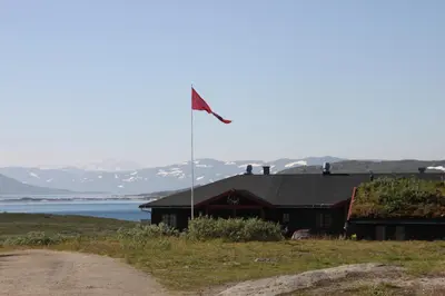 a flag on a pole in front of a building at Tyinholmen Høyfjellsstuer in Eidsbugarden