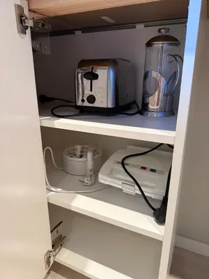 a kitchen shelf with a toaster and a microwave at Cozy basement apartment in Orkanger in Orkanger