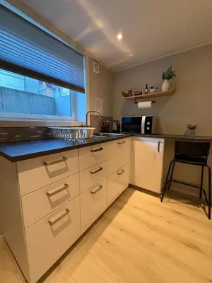 a kitchen with white cabinets and a window at Cozy basement apartment in Orkanger in Orkanger
