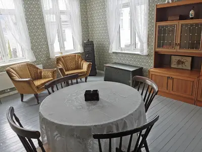 a room with a table and chairs and windows at Unikt og romslig hus perfekt for grupper in Nordfjordeid