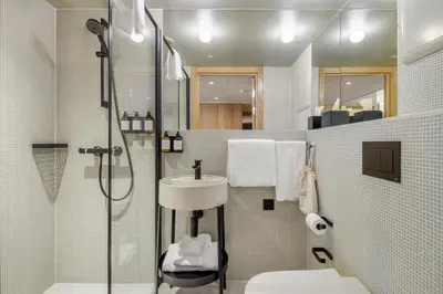 a bathroom with a shower and a toilet and a sink at Skostredet Hotel & Spa in Bergen