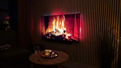 a fireplace in a room with a table and wine glasses at Moderne cityleilighet Sogndal in Sogndal
