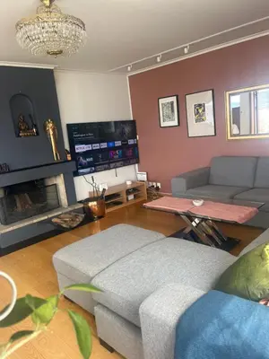 a living room with a couch and a tv at Villa med panoramautsikt, stor uteplass og 100 m fra badestrand in Bergen