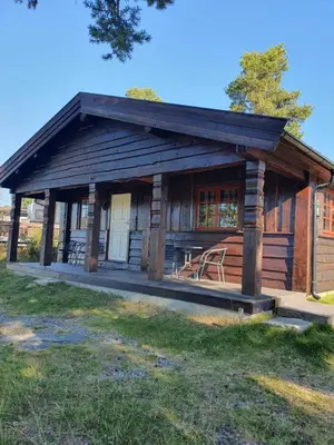 a log cabin with a porch and chairs in it at Bjørgebu Camping AS in Mysusæter