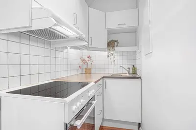 a white kitchen with white cabinets and a sink at Seaside Apt. Catch Crabs from Your Bedroom Window! in Bergen