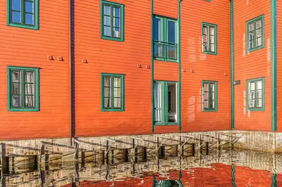 an orange building with a reflection in the water at Ocean-view Haven: Take a swim from your window! in Bergen