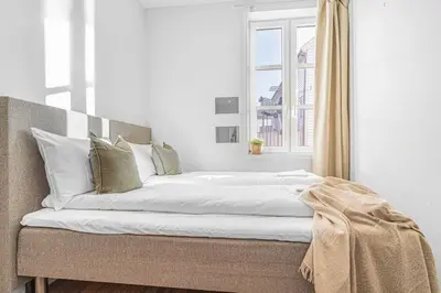 a bed with white sheets and pillows in a room at Ocean-view Haven: Take a swim from your window! in Bergen