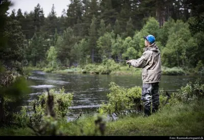 a man standing in a river holding a fishing rod at Bjørgebu Camping AS in Mysusæter