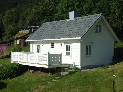 a small white house with a porch on a yard at Gjerdset Turistsenter in Isfjorden