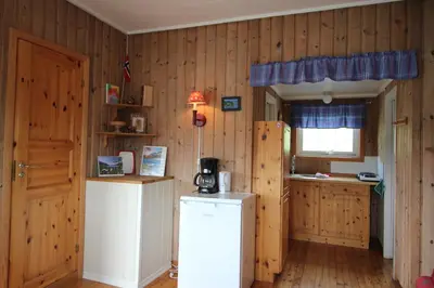 a kitchen with wooden walls and a refrigerator and a window at Gjerdset Turistsenter in Isfjorden