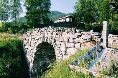 a stone bridge over a river in a field at Gjerdset Turistsenter in Isfjorden