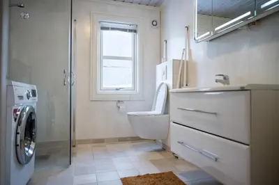 a bathroom with a toilet and a sink and a washing machine at Stranda Fjellgrend - with jacuzzi & 3 bedrooms in Stranda