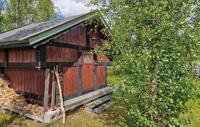 a red barn with a porch next to a tree at Cozy Home In Gol With Sauna in Golsfjellet