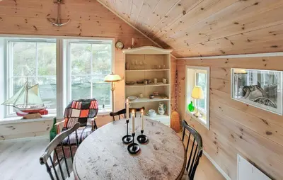 a dining room with a table and chairs in a cabin at 2 Bedroom Cozy Home In Finnås in Grutle